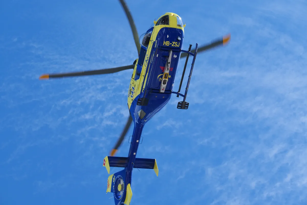Ein blau-gelber Helikopter von unten.